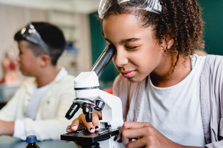 Person looking through microscope 