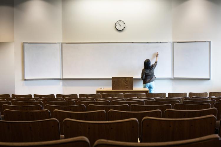 Teacher writing on a white board in an empty classroom