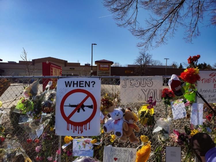 Flowers and signs placed on a fence in honor of a victim of shooting