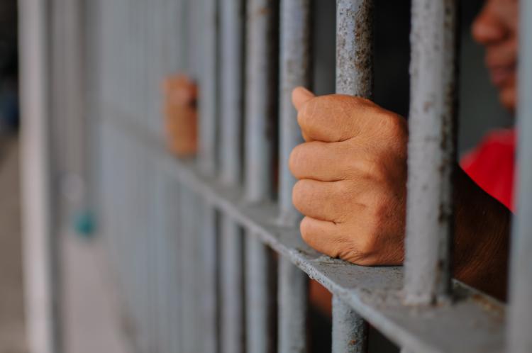 Prisoner holding the bars of his cell